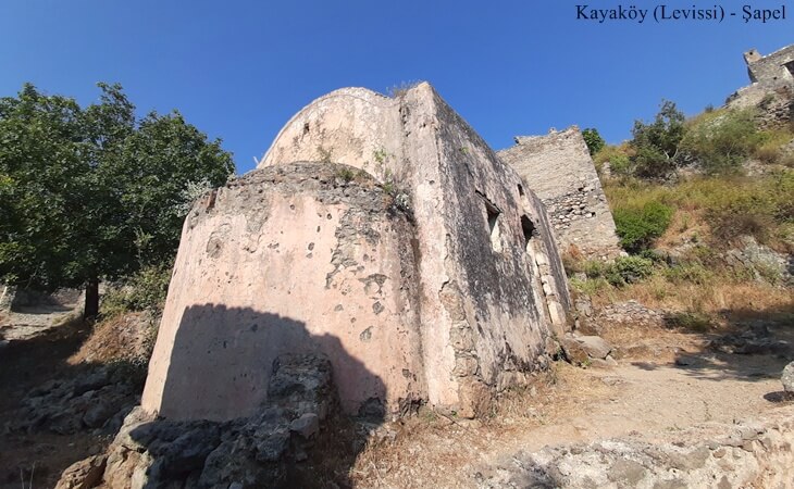 Kayaköy (Levissi)’de yamaçta yer alan küçük pembe tonlu taş şapel ve çevresindeki tarihi kalıntılar.
