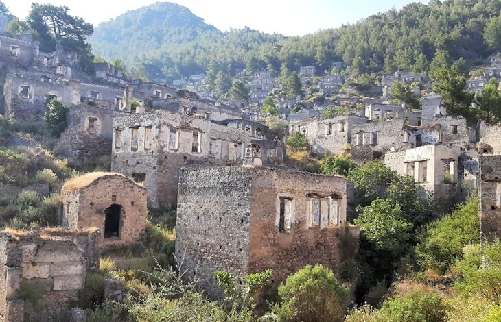 Kayaköy (Levissi)’de yamaç boyunca sıralanmış taş evler ve aralarında yer alan küçük bir şapel kalıntısı.