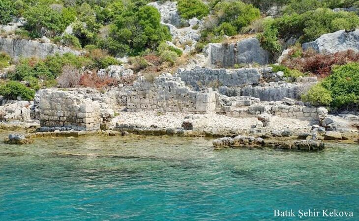 Kekova’da deniz kıyısındaki Batık Şehir kalıntıları, taş duvarlar ve su altına gömülmüş antik yapı izleri