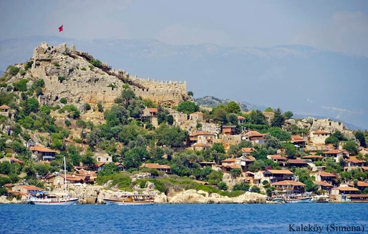 Kekova’da deniz kenarındaki Kaleköy (Simena) yerleşimi ve tepedeki tarihi kale manzarası