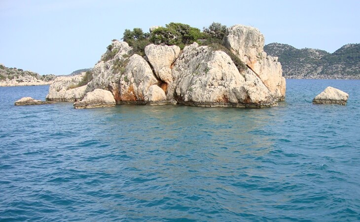 Kekova açıklarında, Akdeniz sularında yer alan kayalık küçük bir ada ve çevresindeki mavi deniz