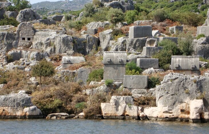 Kekova kıyılarında, kayalık zemin üzerine dağılmış Likya dönemine ait taş lahitler ve mezar kalıntıları