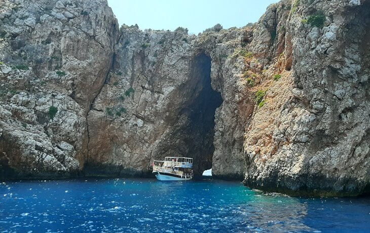 Suluada açıklarında kayalıkların arasında doğal bir kemer (mağara) oluşumu ve bu kemerin önünde demirlemiş bir tur teknesi.