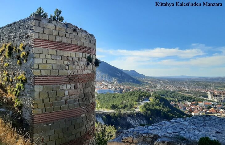kutahya kalesi sur duvari ve tepeden kutahya sehir manzarasi, dag eteklerine yayilan yerlesim ve yesil orman dokusu, tarihi kale gorunumu