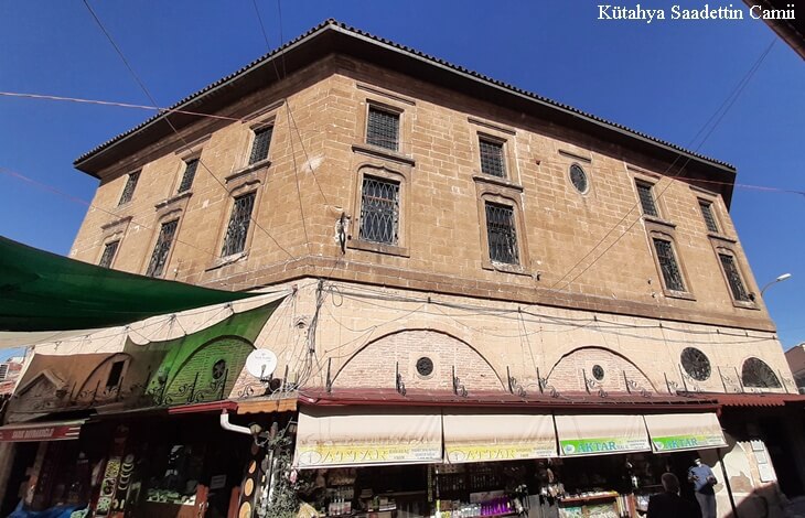kutahya saadettin cami dis cephe goruntusu, tarihi tas mimari, caminin altindaki aktar ve dukkanlar, guneşli gunduz manzarasi
