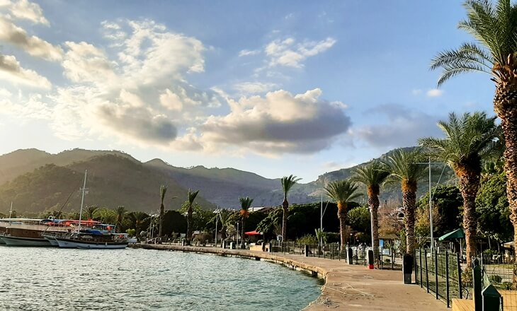 Fethiye sahil şeridinde gün batımına doğru uzanan yürüyüş yolu ve palmiyelerle çevrili marinadan bir görünüm