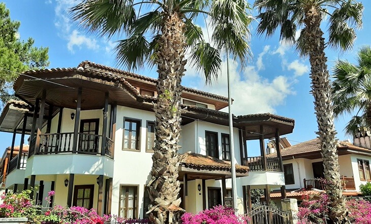 Akyaka&rsquo;daki geleneksel Muğla mimarisiyle inşa edilmiş beyaz badanalı ev ve palmiye ağa&ccedil;ları