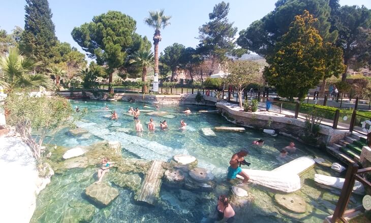 Pamukkale’de antik sütun kalıntıları arasında termal suda yüzen ziyaretçiler