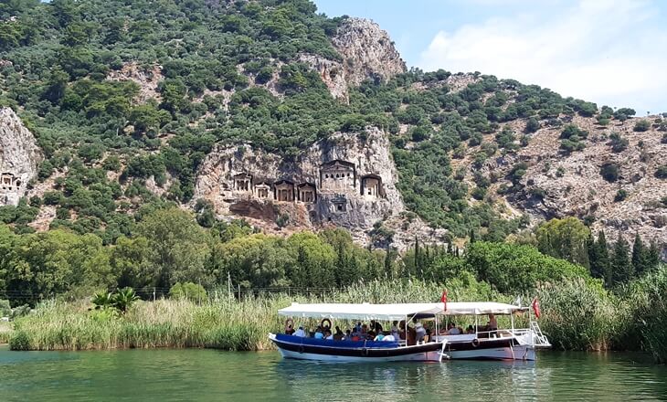 Dalyan Kanalı’nda ilerleyen tekne ve arka plandaki Kaunos kaya mezarları