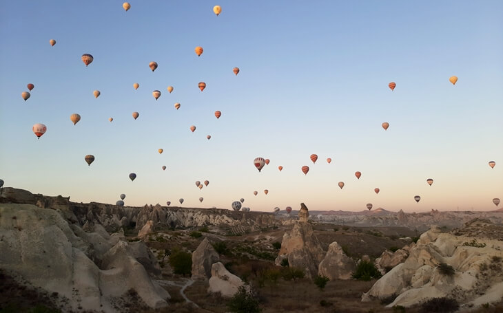 Kapadokya’da gün doğumunda yükselen sıcak hava balonları ve peri bacaları manzarası