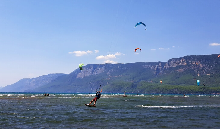 Gökova Akçapınar sahilinde rüzgârla hızlanan kitesurfer ve arka planda Sakar Dağı manzarası