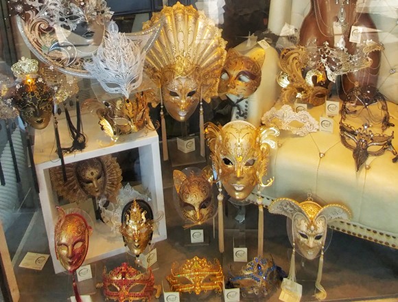 Venedik&rsquo;te Rialto K&ouml;pr&uuml;s&uuml; &uuml;zerindeki d&uuml;kk&acirc;nlarda sergilenen geleneksel Venedik karnaval maskeleri, altın ve renkli detaylarıyla şehrin y&uuml;zyıllardır s&uuml;ren el sanatları geleneğini yansıtan vitrin g&ouml;r&uuml;n&uuml;m&uuml;