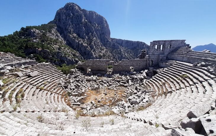 Termessos Antik Kenti – Dağ yamacında yer alan antik tiyatro ve arka planda Güllük Dağı manzarası