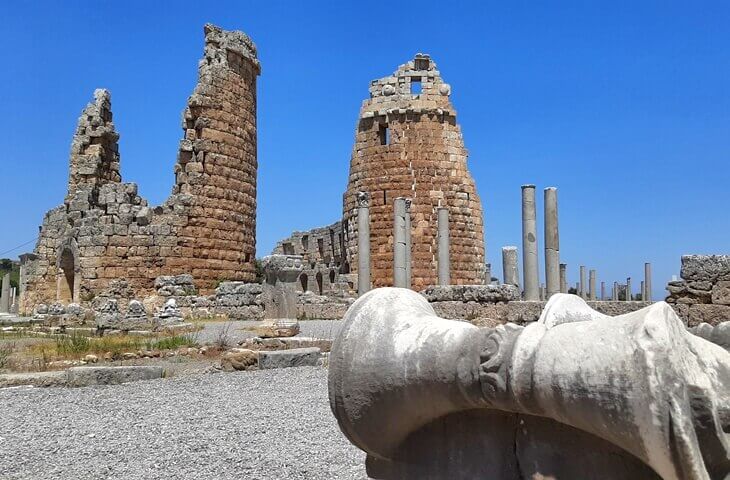 Perge Antik Kenti – Roma dönemine ait yuvarlak kule kalıntıları ve sütunlu cadde manzarası