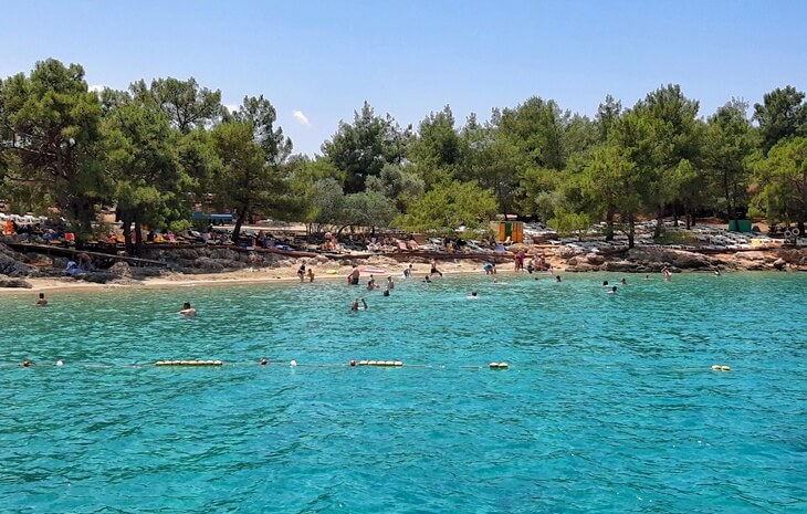 Gökova’daki İncekum Plajı’nda berrak turkuaz deniz ve çam ağaçlarıyla çevrili sakin kumsal.