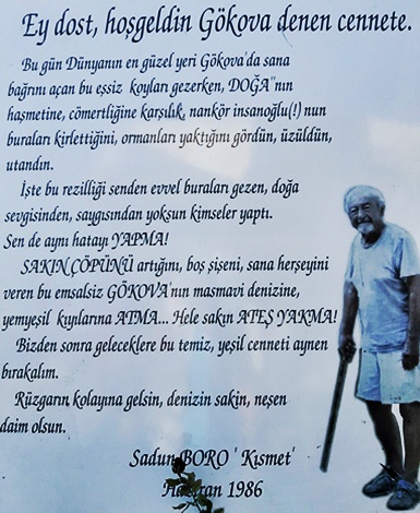 Sadun Boro'nun 1986 yılında Akyaka'da yazdığı çevre duyarlılığı mesajının yer aldığı tabela; yanında elinde bastonuyla Boro'nun siyah beyaz bir fotoğrafı bulunuyor.
