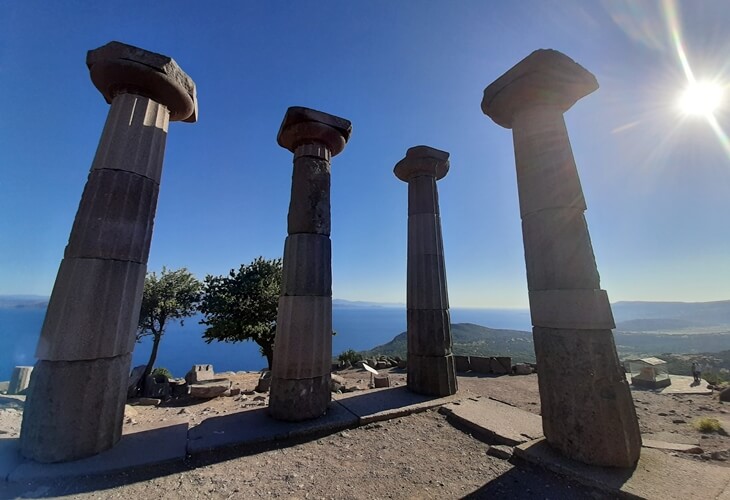 Assos Athena Tapınağı&rsquo;nda ayakta kalan Dor s&uuml;tunları; arkada Ege Denizi ve Midilli silueti, sağ &uuml;stte batmakta olan g&uuml;neş.