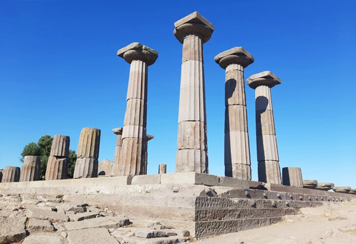 Assos&rsquo;ta Athena Tapınağı&rsquo;nın Dor d&uuml;zenindeki s&uuml;tunları, akropolis &uuml;zerinde mavi g&ouml;ky&uuml;z&uuml;ne karşı.