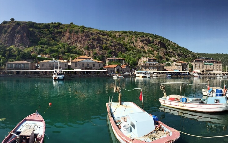 Assos Antik Liman&rsquo;da taş oteller ve kayıklar, sakin deniz manzarası
