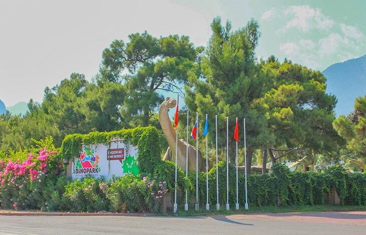Antalya Kemer&rsquo;de yer alan DinoPark&rsquo;ın girişi, bitkilerle &ccedil;evrili duvar ve dev dinozor maketiyle birlikte