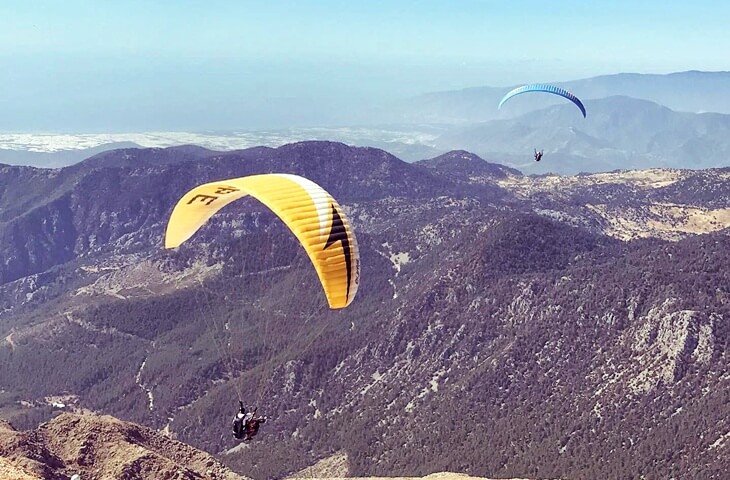 Tahtalı Dağı üzerinde yamaç paraşütü yapan sporcular, arka planda Toros Dağları ve Akdeniz manzarası