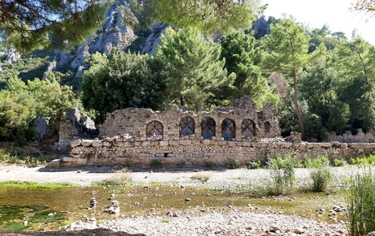 Olympos Antik Kenti’nde Olympos Çayı kenarında yer alan kemerli taş yapı kalıntıları ve çevresindeki doğal bitki örtüsü
