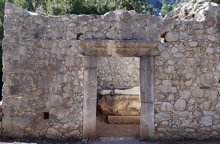 Olympos Antik Kenti’ndeki Batı Nekropol alanında yer alan, taş duvarlı yapıya ait sağlam antik giriş kapısı ve iç kısmında görünen lahit