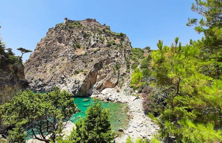Gazipaşa’daki Delikdeniz çevresinde, yeşillikler arasından görünen antik Antiochia ad Cragum kalıntıları ve kayalık koy manzarası.
