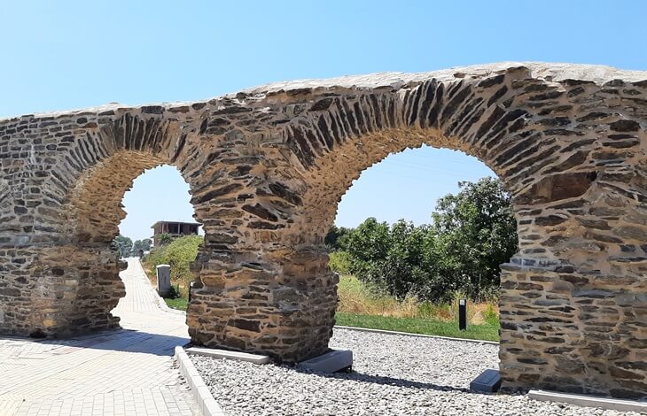 Gazipaşa Selinus Antik Kenti’nde yer alan, restore edilmiş taş kemerli antik su kemeri yapısı, arka planda doğa ve yürüyüş yolu ile birlikte.