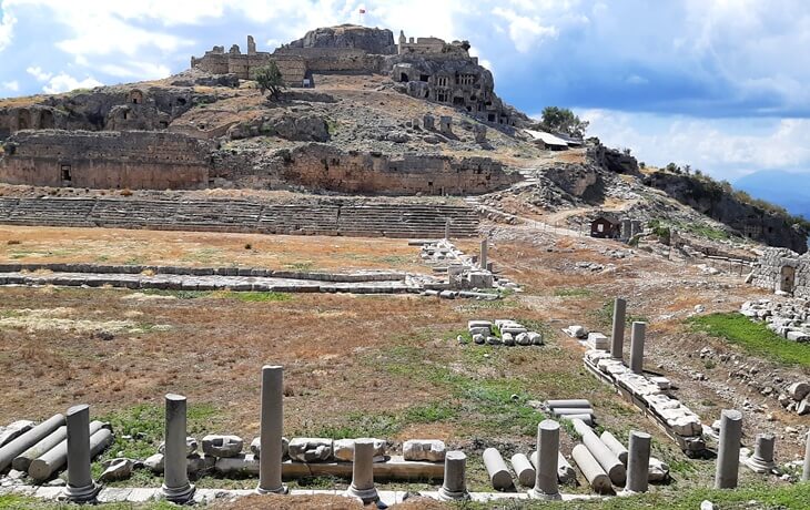 Tlos Antik Kenti’nde tiyatro kalıntıları, sütunlar ve üst kısımda kaya mezarlarının bulunduğu akropol tepesi