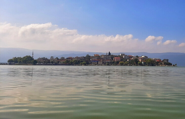 Uluabat G&ouml;l&uuml;&rsquo;nden bakıldığında G&ouml;lyazı K&ouml;y&uuml;&rsquo;n&uuml;n genel silueti ve arka planda dağ manzarası